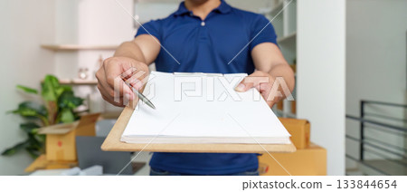 Delivery Confirmation. Person presenting a clipboard for signature, finalizing the delivery. Delivery Confirmation. Person presenting a clipboard for signature, finalizing the delivery. 133844654
