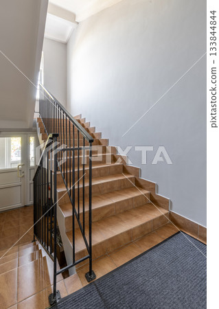 Bright Staircase Interior with Tiled Steps and Metal Railing 133844844