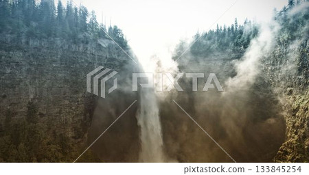 Flat design waterfall scene is showing backlit cascade plunging into canyon, with evergreen trees 133845254