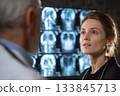 A female doctor holds a consultation with a colleague looking at brain X-ray images 133845713