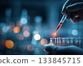 Close-up of a scientist's hands carefully manipulating a pipette in a test tube 133845715