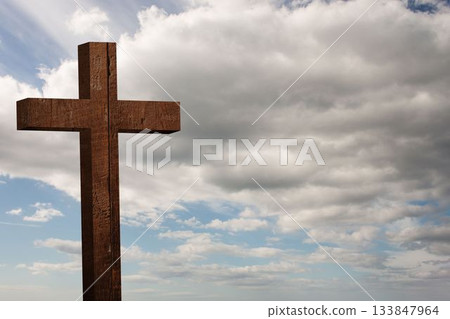 Wooden cross standing against cloudy sky in flat design, highlighting rough-hewn texture Wooden cross standing against cloudy sky in flat design, highlighting rough-hewn texture 133847964