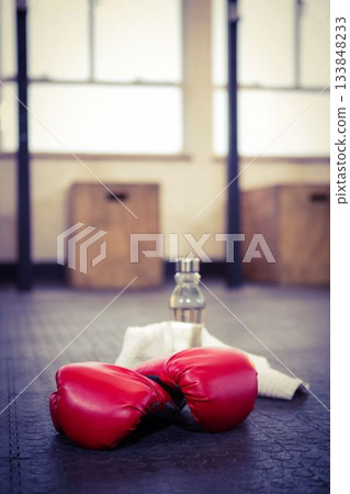 Boxing gloves with bottle on flooring at gym 133848233