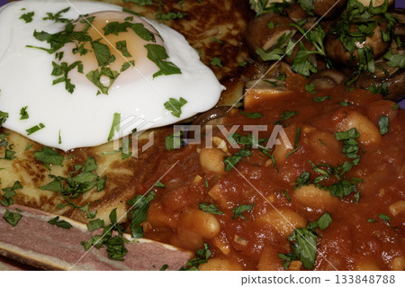 Close up of Fresh egg frying in a pan with golden yolk with bacon and home made beans fried breakfast Close up of Fresh egg frying in a pan with golden yolk with bacon and home made beans fried breakfast 133848788