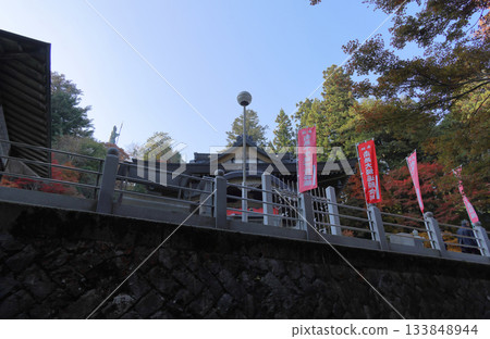 The main hall and autumn leaves near the Bishamonten statue seen from the approach to Unpenji Temple, the 66th temple of the Shikoku Pilgrimage 133848944