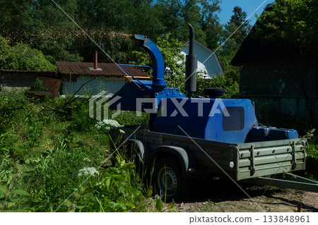 An operator loads tree branches into a wood chipper. 133848961