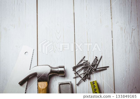 Flat illustration showing claw hammer with wooden handle beside hand saw, nails, tape, copy space Flat illustration showing claw hammer with wooden handle beside hand saw, nails, tape, copy space 133849165
