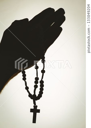 Solhouette hand with rosary praying Solhouette hand with rosary praying 133849204