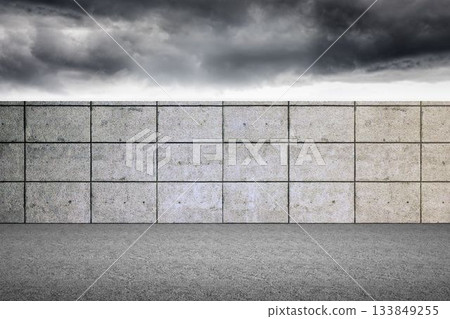 Flat design tiled concrete wall is stretching across open paved ground, with stormy clouds overhead 133849255