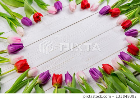 Oval multicolored tulip wreath is being shown in flat design on white wooden planks, copy space Oval multicolored tulip wreath is being shown in flat design on white wooden planks, copy space 133849392
