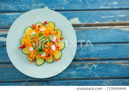 Fresh salad in circle plate on wooden table 133849444
