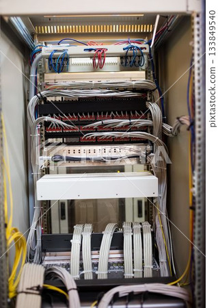 Network rack is showing 3D render of server room, featuring patch panels and bundled colored cables 133849540