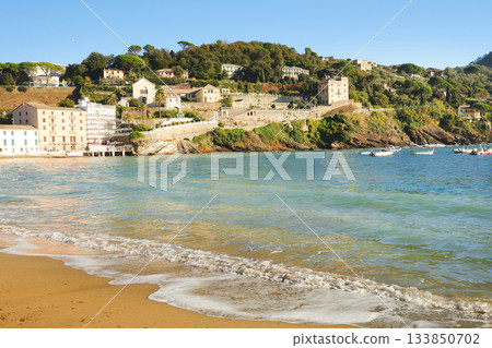 Traditional buildings and houses in seaside bay of Silence in autumn, Sestri Levante. Ligurian nature and architecture. Blue sky, sandy beach, clouds, and backdrop for design. 133850702