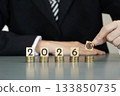 business people places a target block on stacks of coins beside number of year 2026 on wooden cubes, symbolizing investment strategy, financial planning, revenue goals, growth, execution, success 133850735