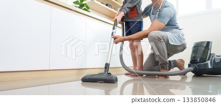 Home Cleaning. Father and son vacuuming floor together. Home Cleaning. Father and son vacuuming floor together. 133850846