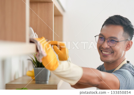 Home Cleaning. Man smiling while organizing shelves. 133850854