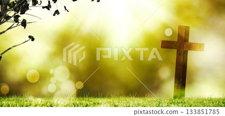 Wooden cross is standing in sunrise meadow, showcasing soft sunlight rays and lens flares Wooden cross is standing in sunrise meadow, showcasing soft sunlight rays and lens flares 133851785