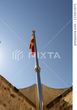 metal flagpole with the flag of Spain on the highest part of a castle tower. metal flagpole with the flag of Spain on the highest part of a castle tower. 133852071