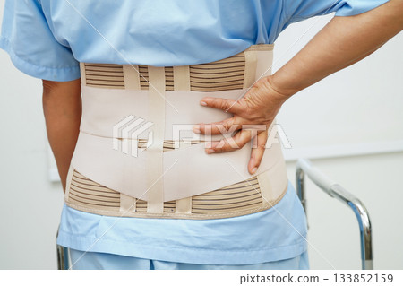 Asian woman wearing lumbar support pain back and use walker in hospital. Asian woman wearing lumbar support pain back and use walker in hospital. 133852159