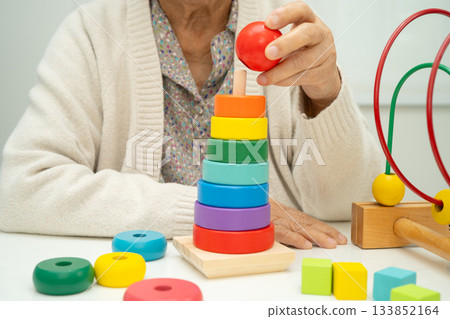 Asian elderly woman playing enhancing skill board game. Asian elderly woman playing enhancing skill board game. 133852164