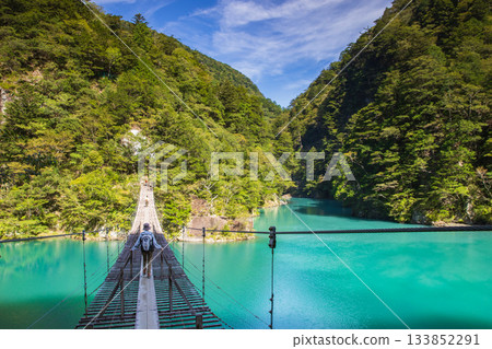 The dream suspension bridge spanning the surface of the Emerald Green lake The dream suspension bridge spanning the surface of the Emerald Green lake 133852291