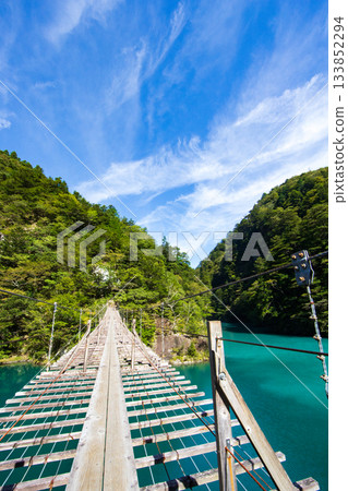 The dream suspension bridge spanning the surface of the Emerald Green lake 133852294