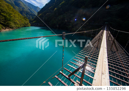 The dream suspension bridge spanning the surface of the Emerald Green lake The dream suspension bridge spanning the surface of the Emerald Green lake 133852296
