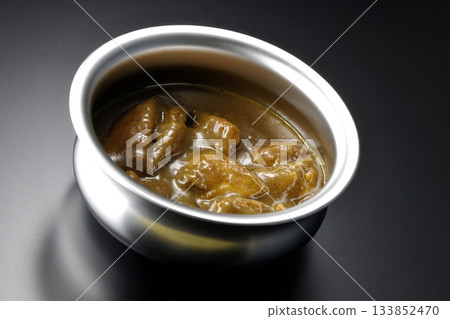 Chicken curry served in silver dish photographed against a black background Chicken curry served in silver dish photographed against a black background 133852470