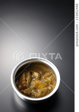 Chicken curry served in silver dish photographed against a black background Chicken curry served in silver dish photographed against a black background 133852498