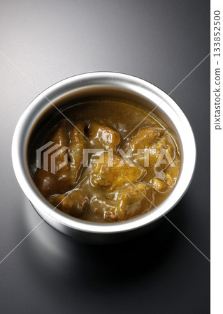 Chicken curry served in silver dish photographed against a black background Chicken curry served in silver dish photographed against a black background 133852500