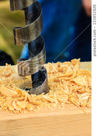 Metal machine drilling in wooden board 133852926