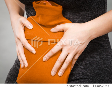 Girl having stomach ache, holding hot water bottle Girl having stomach ache, holding hot water bottle 133852934