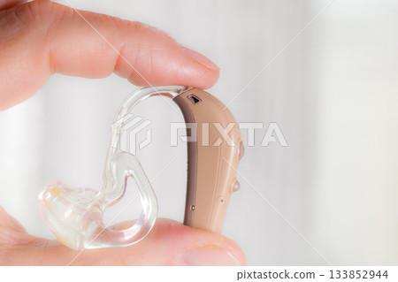 senior person holding hearing aid closeup senior person holding hearing aid closeup 133852944