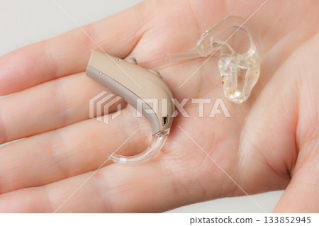 senior person holding hearing aid closeup senior person holding hearing aid closeup 133852945
