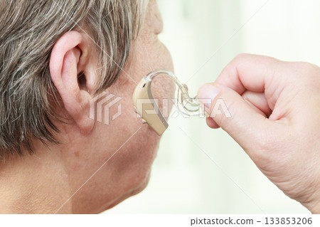 Closeup senior woman using hearing aid 133853206