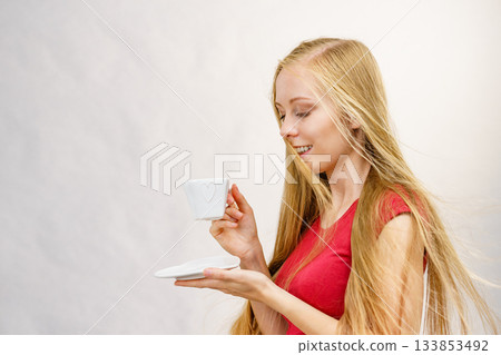 Blonde girl blowing hair holds coffee cup Blonde girl blowing hair holds coffee cup 133853492