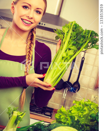 Woman in kitchen with green vegetables Woman in kitchen with green vegetables 133853659
