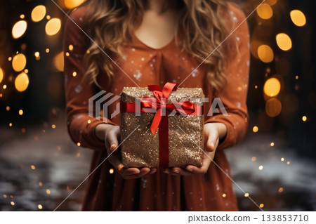 closeup of gift in girl hands, outdoor, evening street, festive lights, Christmas or New Year holidays 133853710