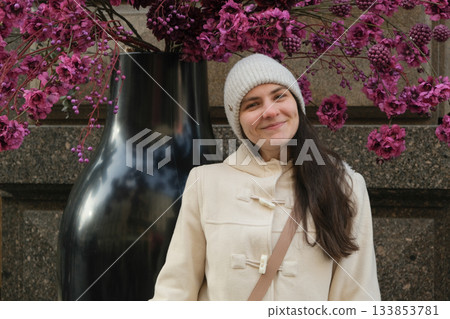 Smiling Woman in Winter Coat Posing by a Large Floral Arrangement. 133853781