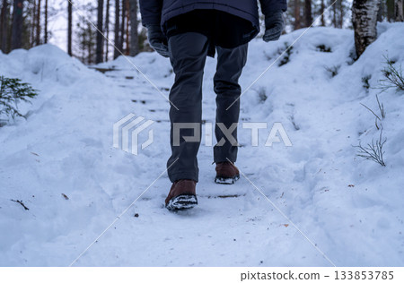 man hiking on snowy winter trail with snow covered boots in lapland man hiking on snowy winter trail with snow covered boots in lapland 133853785