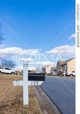 A white mailbox with the number 155 on it sits on the side of a street 133854255