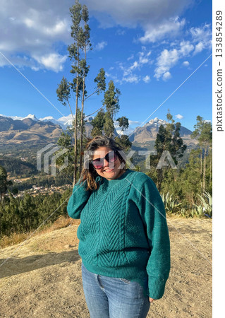 A woman is standing on a hillside wearing a green sweater and sunglasses A woman is standing on a hillside wearing a green sweater and sunglasses 133854289