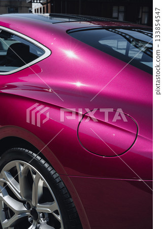 Sleek design of a vibrant pink sports car caught in sunlight on a city street Sleek design of a vibrant pink sports car caught in sunlight on a city street 133854547