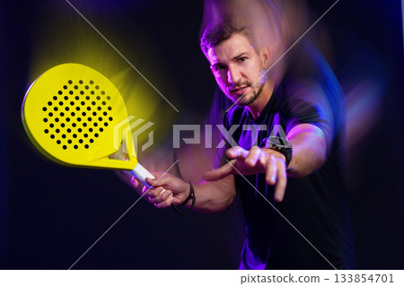 Young man playing dynamic paddle sports with a bright yellow paddle in motion indoors Young man playing dynamic paddle sports with a bright yellow paddle in motion indoors 133854701