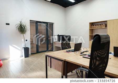 Modern office interior with desktop computers and natural light during the day Modern office interior with desktop computers and natural light during the day 133854716