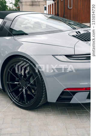 Sleek gray sports car parked on a modern street during a sunny day 133854730