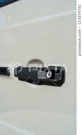Car door handle close-up showing lock and surface details on a white vehicle Car door handle close-up showing lock and surface details on a white vehicle 133854792