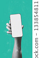 Hand holding blank smartphone against a vibrant teal background in modern design 133854811
