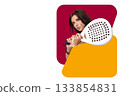 Young woman practicing padel with focus and determination in a vibrant setting 133854831
