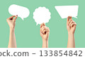 Creative hands holding empty speech bubbles on a light green background for communication ideas 133854842
